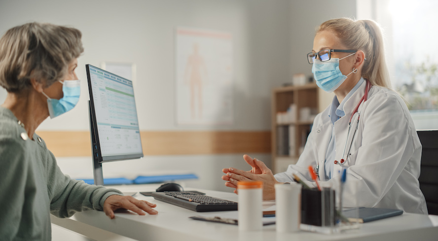 Médecin et patiente masquées en discussion dans une salle d’examen