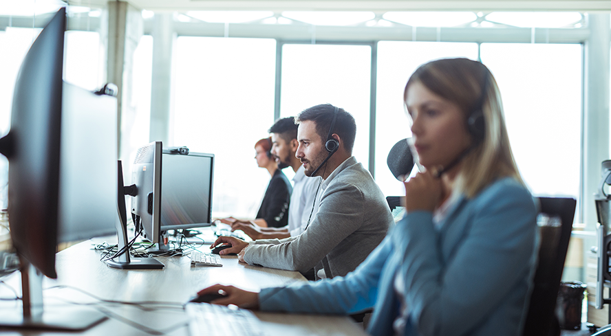 Équipe de professionnels répondant à des appels devant leur écran d’ordinateur.