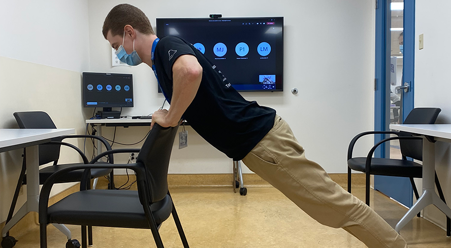 Professionnel en posture d’exercice physique devant un écran d’ordinateur.